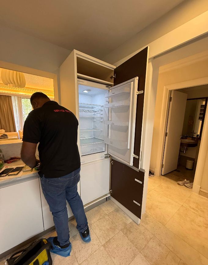 Technician repairing a built-in refrigerator in Dubai